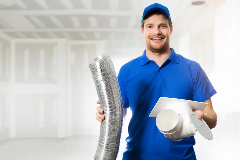 Smiling technician holding ventilation ducting and installation components.